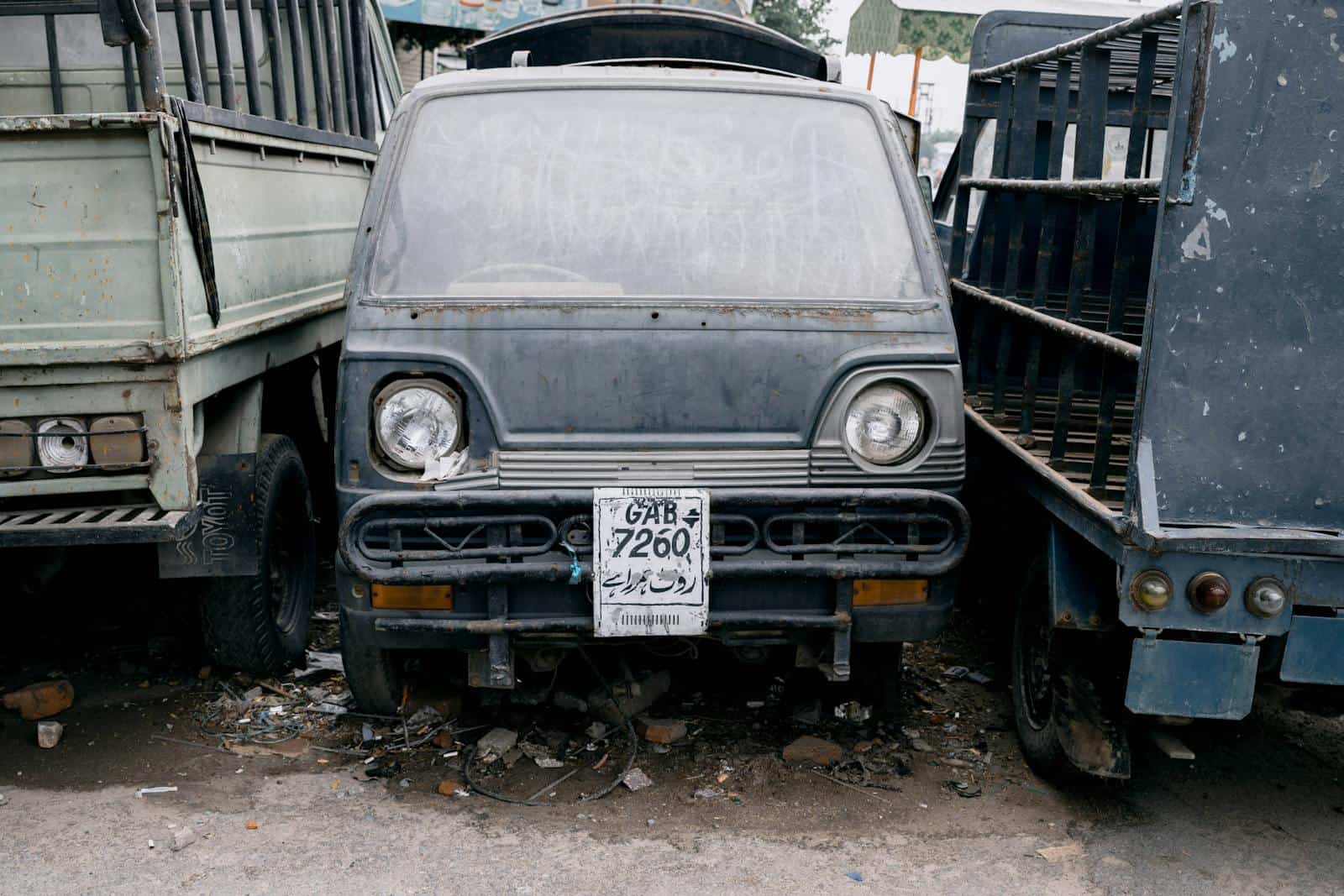 A close-up of a weathered truck with a faded license plate parked on a Faisalabad street.